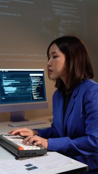 Asian female coder developing software on computer