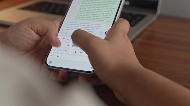 Woman's hand chatting and typing on a smartphone, macro closeup. Unrecognisable human typing a text message, tapping the touchscreen keyboard using the WhatsApp application, a social media.