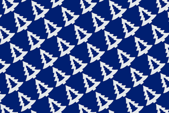 Christmas tree repeat seamless diagonal pattern design on blue background. Frosted white symbols of Xmas, decoration for wrapping paper or greeting card.

