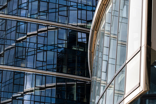 Overlapping glass facades and connecting metal structures forming an intricate architectural composition with deep blue reflections and intersecting lines
