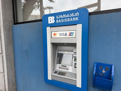 Tbilisi, Georgia - September 01, 2026: Basisbank ATM displays Georgian and Latin lettering, Mastercard and Visa logos, and a keypad within a blue wall enclosure