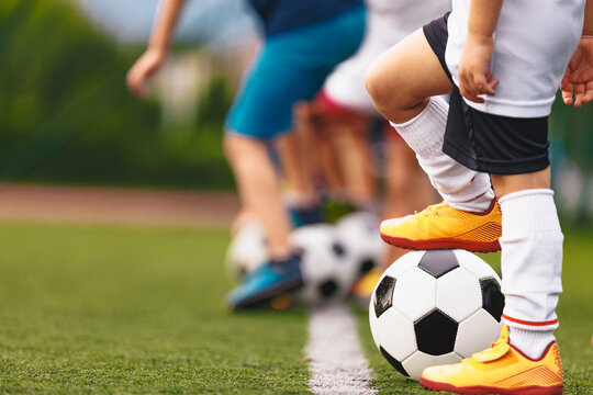 Close-Up of Junior Football Player Foot Resting on Soccer Ball in Yellow Cleats and White Socks - Outdoor Grass Pitch Drill