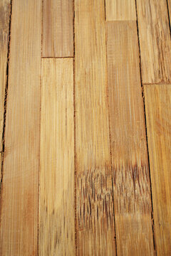 Natural light brown bamboo flooring planks stacked vertical parallel light texture pattern.