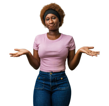 Young african american woman in pink clothes with clueless, confused expression, hands and arms raised in a puzzled shrug in studio