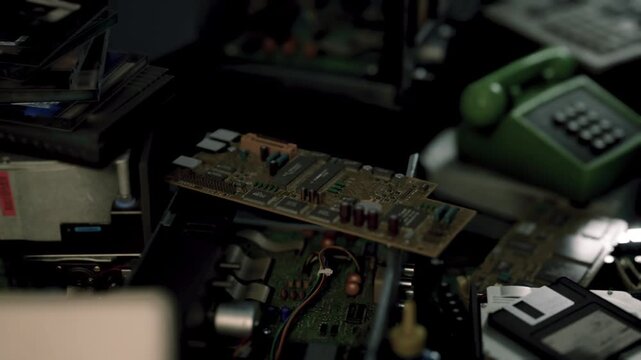 Amidst a cluttered workshop, circuit boards and old gadgets sit quietly, showcasing the charm of outdated technology. Dust and shadows create a nostalgic atmosphere of past inventions.