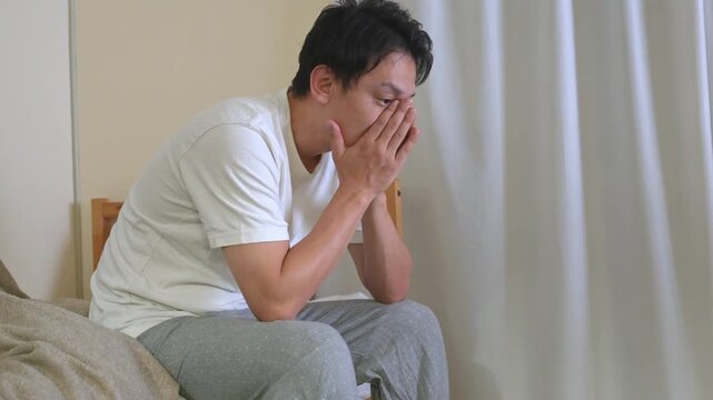 顔を手で覆い、体調の悪そうな男性
