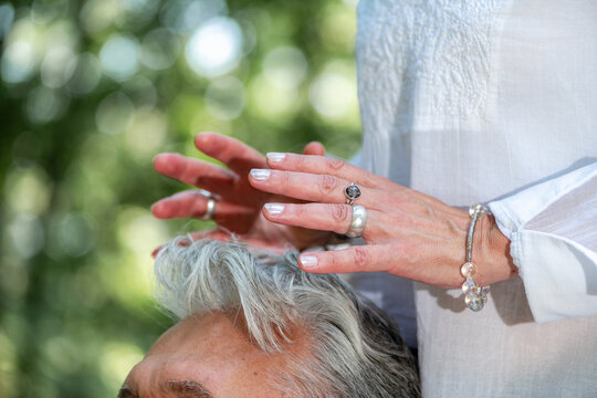 Close-up of a practitioner holding hands above the head during a crown chakra healing practice, symbolizing spiritual awareness, energy balancing, mindfulness, and holistic wellbeing.