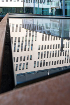 White building facade reflected in a glass surface with repeated windows and geometric distortion creating a layered view of modern urban architecture