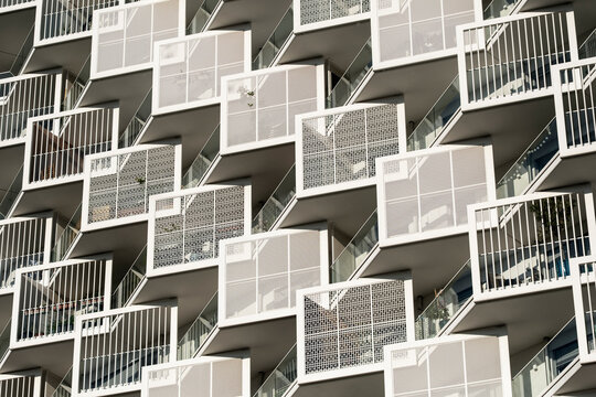White balconies and railings arranged across a modern apartment facade creating a dense geometric pattern in contemporary residential architecture