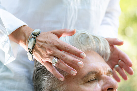 Hands around the forehead and head during a guided energy healing practice, encouraging spiritual awareness, mindfulness, emotional balance, and deep relaxation.