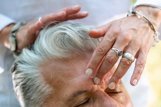 Practitioner holding hands around the forehead and crown during a guided spiritual healing practice centered on chakra balance, mindfulness, and energetic connection.