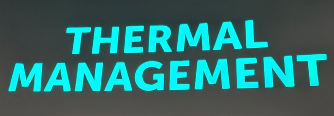 Large turquoise illuminated text reading “THERMAL MANAGEMENT” displayed on a dark background. The striking design highlights engineering and electronics themes, symbolizing cooling systems. © Johari