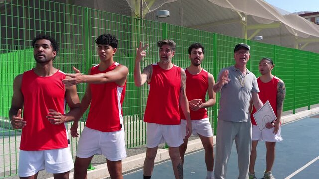 Disappointed basketball players gesturing and complaining to their coach about a bad play on an outdoor court in slow motion