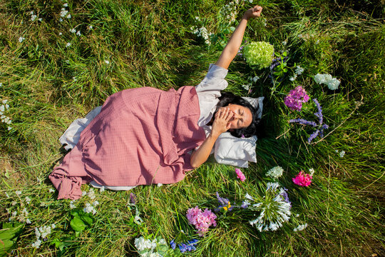 A woman wakes up and stretches in a peaceful flower meadow outdoors