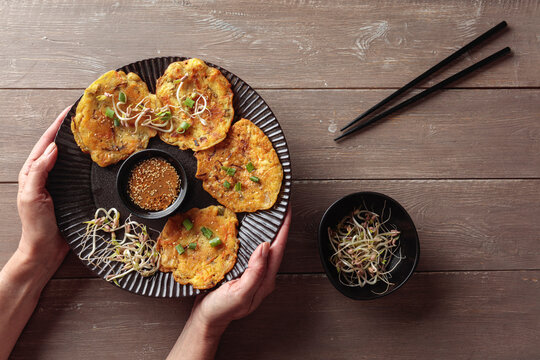 Woman holds plate of vegan mung bean pancake with kimchi