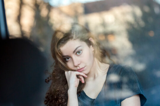 Portrait of pensive teenage girl behing windowpane