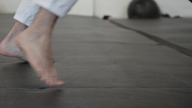 Lifting heavy truck tyre on gym floor mat barefoot martial arts gi training