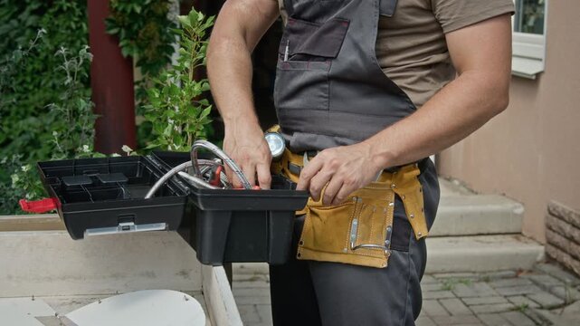 Unrecognizable repairman organizing tools from toolbox into tool belt. Visual suits commercial advertising for plumbing services, home renovation, or skilled trade promo