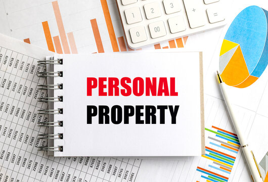 Personal property text on a spiral notebook with calculator, pen and financial charts, concept of assets, ownership and valuation