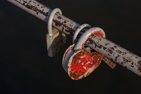 Old rusty heart shaped padlock locked on a metal railing. Nostalgia, passing time and relationship concept with dark background