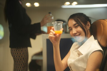 Seatmates clinking plastic cups smile at each other over their juice in the passenger cabin of a plane, showing the social side of flying, good for celebration and travel themes © ultramansk