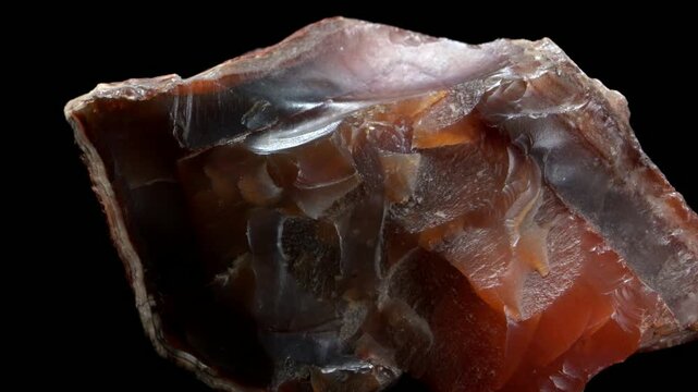 Carnelian (chalcedony coloured by iron oxide) rotating slowly against a black background