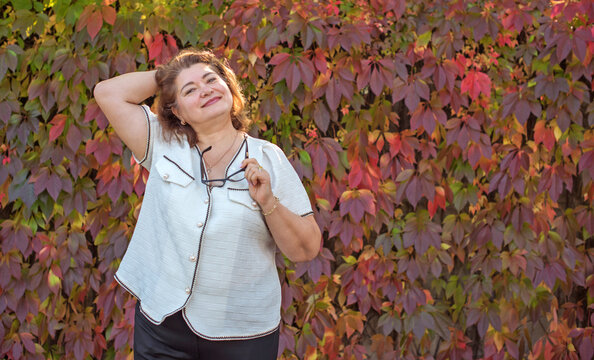 Happy plus size mature woman in her 50s smiling outdoors in an elegant classic outfit. Positive lifestyle portrait celebrating mature beauty, confidence, happiness, self acceptance and an active 55s