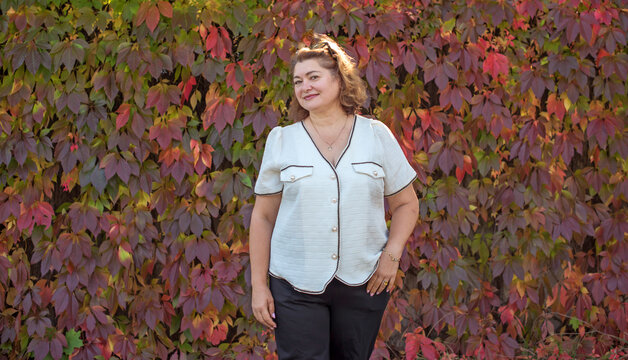 Happy plus size mature woman in her 50s smiling outdoors in an elegant classic outfit. Positive lifestyle portrait celebrating mature beauty, confidence, happiness, self acceptance and an active 55s