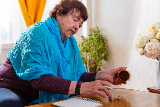 Senior Caucasian woman rolling dice and focusing on game results. Indoor setting. Concept of leisure and aging.