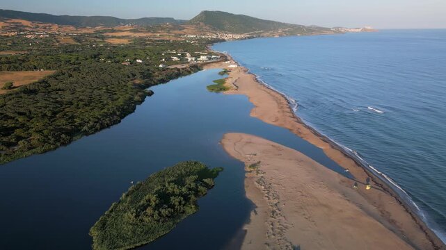 Panoramic aerial view of the mouth of the Coghinas River where it flows into sea at San Pietro a Mare in Sardinia, featuring an elongated sandy spit, a small green islet, and hills in the background