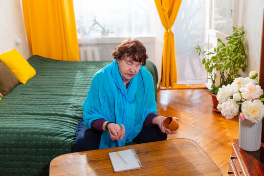 Older woman playing dice game while sitting indoors. Relaxed moment and focus. Concept of aging and lifestyle. Top view