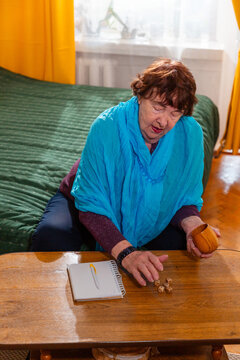Senior woman playing dice game at home. Focus and calm mood. Concept of aging and activity. Vertical