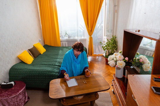 Older woman enjoying dice game in a quiet home setting. Relaxed mood and engagement. Concept of wellbeing and comfort. Wide shot