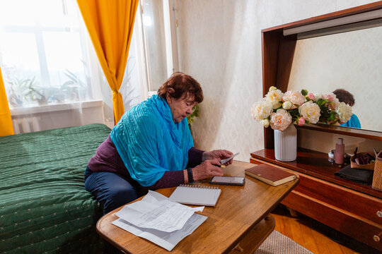 Elderly woman managing pension income with notebook and calculator. Calm planning and confidence. Concept of money control and savings.