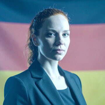 Young european woman in business suit posing with german flag backdrop