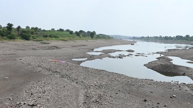 completely dry rocky riverbed winding through a parched rural landscape. This footage highlights severe drought, water scarcity, and the impact of climate change.