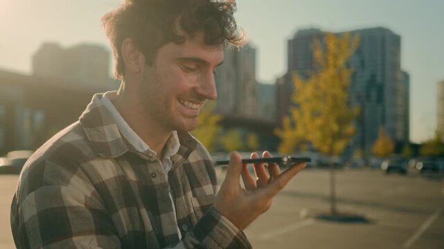 Handsome Caucasian man walking in city recording voicemail on smartphone smiling businessman guy chatting friends using virtual assistant app mobile messenger happy male record audio message outdoors