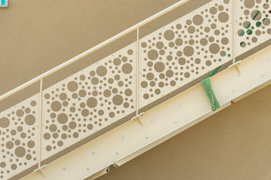 Detail of white staircase stringer with circular perforated pattern railing