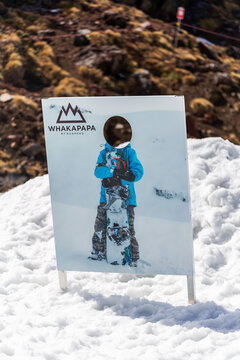 Snow-covered promotional photo board for snowboarders displayed at Whakapapa Ski Field on Mount Ruapehu, New Zealand, inviting visitors to create souvenir photographs