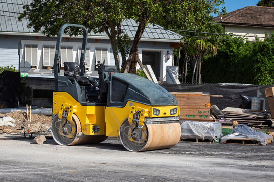 Road construction roller parked outdoors in front residential building