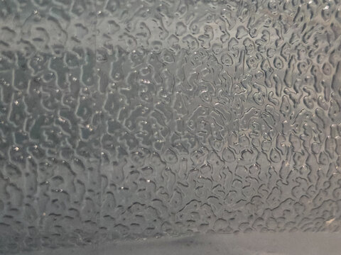 Extreme close-up macro texture of a grey synthetic material featuring irregular embossed bumpy patterns, ridges, and specular light highlights. Ideal target for industrial design backgrounds, modern b