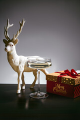 Champagne in coupe glass with white reindeer figurine and Christmas gift box on table © ShapeImages