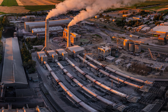 drone view in spherical projection of large cement plant with iconic long horizontal rotary kilns, tall smokestacks and industrial buildings.