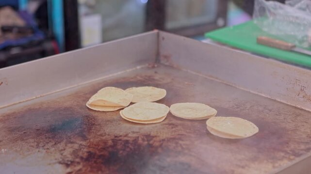 Fresh corn tortillas cooking on a hot comal griddle