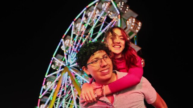 Happy couple enjoying a piggyback ride at amusement park