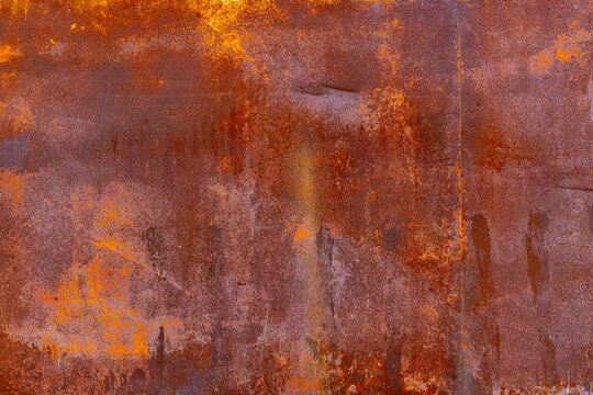 Detailed close-up of a rusted metal surface showcasing extensive patina. The rough texture features varying shades of brown, orange, and yellow, highlighting oxidation effects.