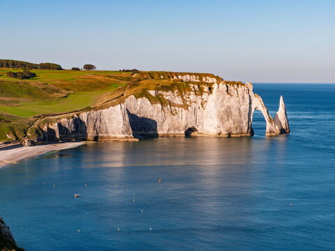 Le Havre, France - 30.06.2015: Massive white chalk cliffs with natural arch and sea stack under clear blue sky in Normandy coastline