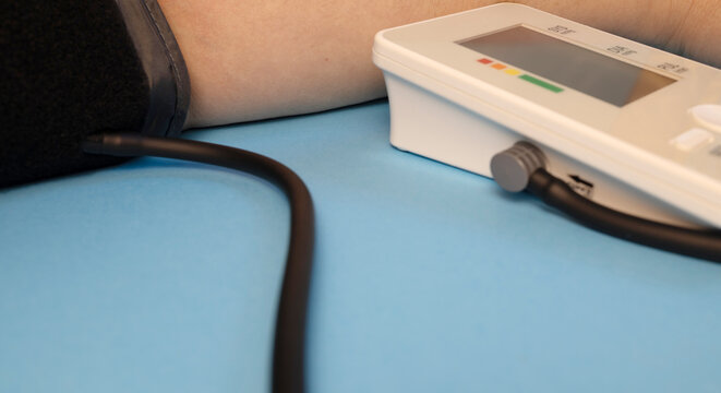 Close-up of a digital blood pressure monitor connected to an arm cuff during measurement. Home healthcare, hypertension monitoring and medical equipment concept.