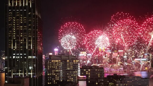 Fireworks bursting over Hong Kong skyline at night, tight telephoto framing