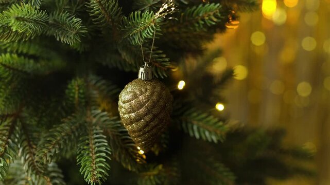 Woman decorating Christmas tree, hanging golden Christmas ornaments.